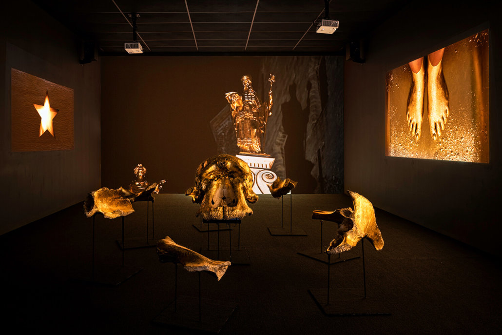 Installation view of Movement III, from left: Berni Searle, Shimmer (2012–13). Installation (5 HD video projections and gold-leafed elephant bones). Southern: a Contemporary Collection. © Berni Searle. Photo Graham De Lacy